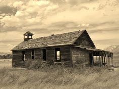 an old run down building in the middle of a field with a bell tower on top