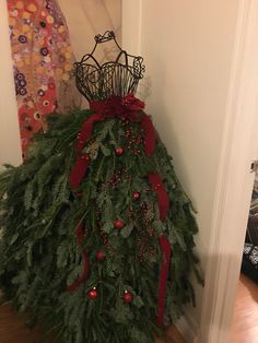 a christmas tree made out of evergreen branches and red berries with a crown on top