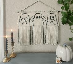 a wall hanging with three ghostes on it next to candles and a candle holder