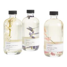 three bottles filled with different types of liquids and flowers on top of each other