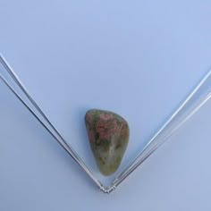 two metal needles and a rock on a white surface with some rocks in the background