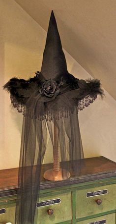 an old dresser has a black hat on top of it, and is decorated with feathers