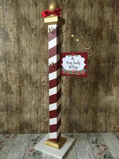 a red and white striped pole with a sign on it that says merry christmas in front of a wooden wall