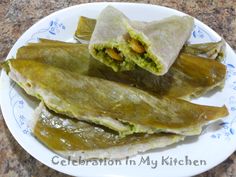 some food is on a white plate with blue and white designs around it, including an eggplant wrap