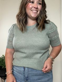 a woman standing in front of a white wall with her hands on her hips and smiling