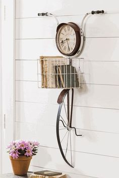 a clock mounted to the side of a wall next to a potted plant on a table