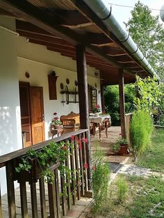 an outside view of a house with flowers on the front porch and tables in the back