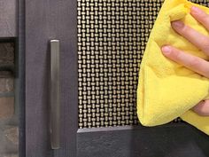 a person wiping up with a yellow microfit towel on a black surface next to a metal door