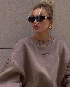 a woman with blonde hair wearing sunglasses and a sweatshirt