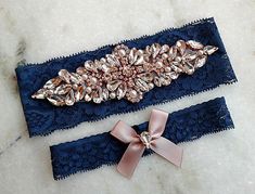 two blue garters with pink bows and crystal broochies on them sitting on a marble surface