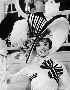 a woman in a dress and hat posing for the camera with two hats on her head