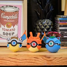 three toy figurines sitting on top of a wooden shelf next to a pineapple