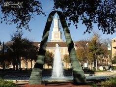 a fountain in front of a building with a clock tower on it's side