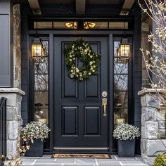 a black front door with wreaths on it