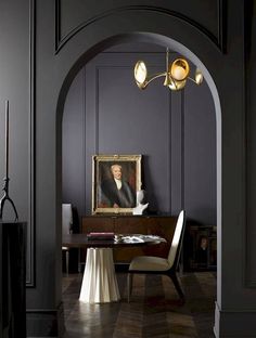 an arch in a room with a painting on the wall next to a table and chairs