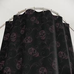 a black curtain with purple skulls and swirls on it, hanging from a metal rod