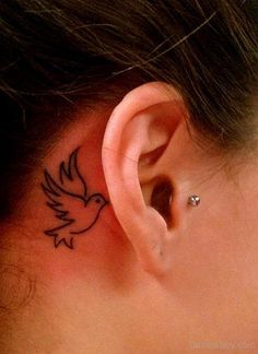 a woman's ear with a small bird tattoo on it