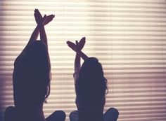 two women standing in front of a window with their hands up