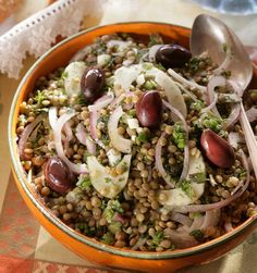 an orange bowl filled with lentils, onions and other vegetables on top of a table