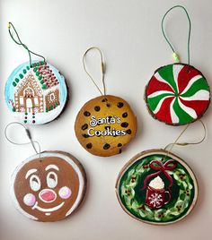 four christmas ornaments are hanging on a white wall, one is decorated with cookies and the other has an ornament that says santa's cookies