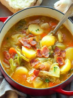 a red pot filled with soup next to bread