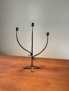 a metal candelabra sitting on top of a wooden table next to two candles