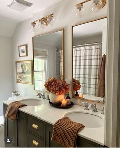 a bathroom with two sinks, mirrors and candles on the counter top in front of it