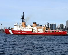 a large red and white boat floating on top of the ocean next to a city