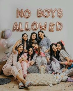 a group of women sitting next to each other in front of a sign that says no boys allowed