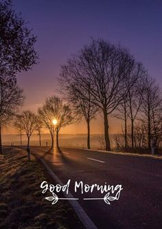 the sun is setting behind some trees on the side of the road that says good morning