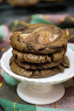 a stack of cookies on a white plate with chocolate swirled in the middle and frosting