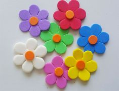 four different colored flowers on a white surface with one flower in the middle and two petals at the bottom