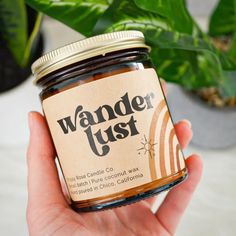 a hand holding a jar of peanut butter in front of a potted plant with the label wander just on it