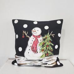 a pillow with a snowman holding a christmas tree on it's back and polka dots