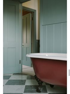 a bath tub sitting on top of a checkered floor next to a green door