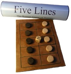 a wooden board game set with dices and pieces on it, next to a book that says five lines