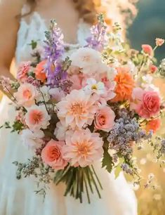 a woman in a white dress holding a bouquet of pink and purple flowers on her wedding day