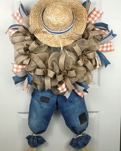 a scarecrow door hanger with a straw hat on it's head and blue jeans