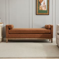 a brown couch sitting in front of a painting on the wall next to a chair