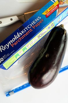 an eggplant sitting on top of a table next to a package of food