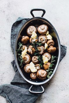 a pan filled with mushrooms and cheese on top of a table next to a cloth