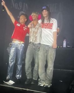 three young men standing on top of a stage