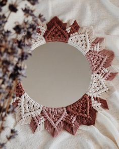 a round mirror sitting on top of a table next to a vase filled with flowers