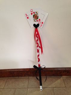 a pair of playing cards tied up to a wall with a red and white ribbon