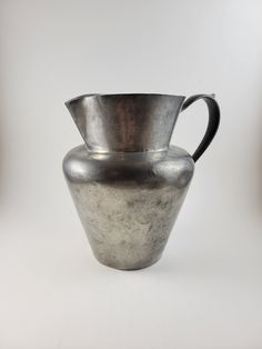 a silver vase sitting on top of a white table