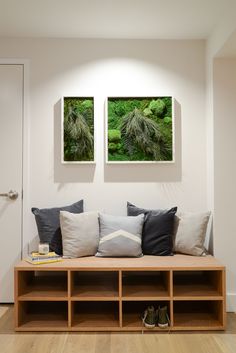 two paintings hang on the wall above a wooden bench with pillows and other decorative items