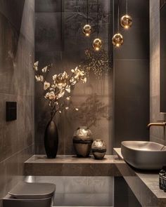 a modern bathroom with black and gold fixtures, marble counter tops, and an elegant vase filled with flowers