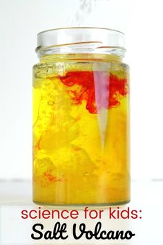 a jar filled with yellow liquid sitting on top of a white table next to an orange and