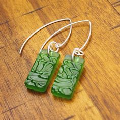 green glass earrings with silver hooks on a wooden table