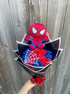 someone is holding a bouquet of flowers in front of a wooden fence with a spiderman on it